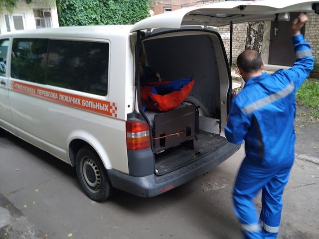 Сотрудник TaxiMed открывает багажник санитарного автомобиля